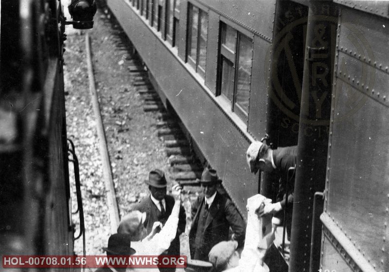 VGN. Appears to be taken from caboose looking down as men load/unload something on passenger car. Date/location unknown
